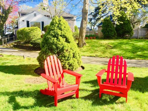 two red chairs sitting in the grass in a yard at Sesuit Harbor House in East Dennis