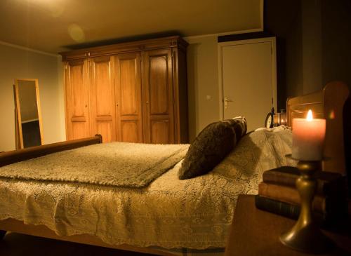 um quarto com uma cama e uma vela sobre uma mesa em 'T Dagwant em Geraardsbergen