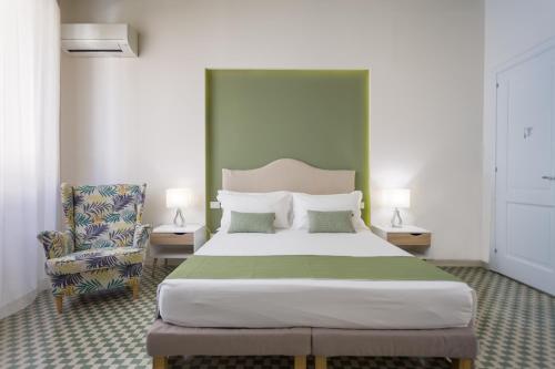 een slaapkamer met een groot bed en een stoel bij B&B Kalavrìa in Reggio di Calabria