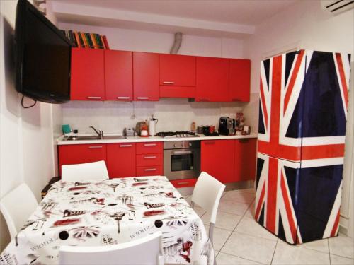 a kitchen with red cabinets and a table with a flag at LONDON BY SEA in Porto Recanati