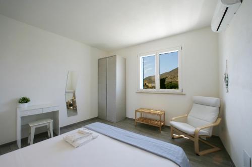 a bedroom with a bed and a chair and a window at Corte della Cava in Favignana