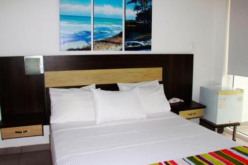 a bedroom with a bed with three pictures above it at Hotel Anamela in Maní