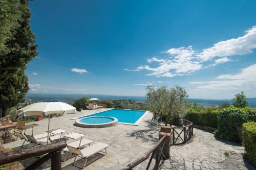 un patio al aire libre con piscina, sillas y sombrilla en Podere San Martino, en Montevettolini