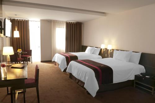 a hotel room with two beds and a table at Arawi Miraflores Prime in Lima