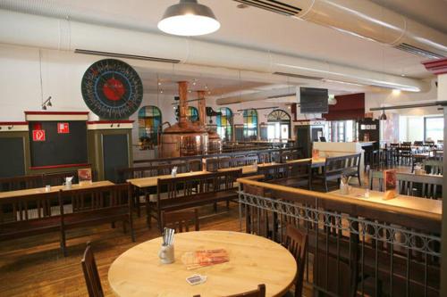 an empty restaurant with wooden tables and chairs at Brau Art Hotel in Neckarsulm