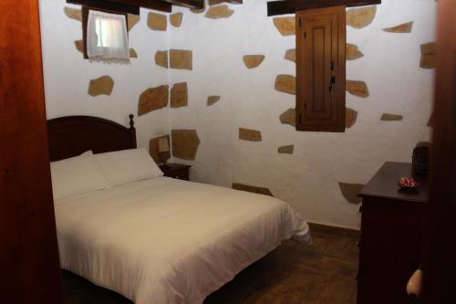 a bedroom with a white bed and a wooden cabinet at Villa Cantos Colorados in Ingenio