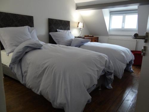 Duas camas com cobertores brancos e almofadas num quarto em Le 4 em Bayeux