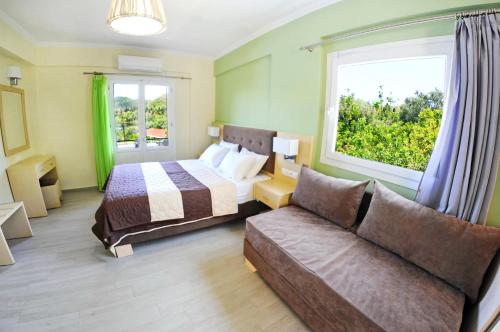a bedroom with a bed and a couch and a window at Vliho Bay Suites & Apartments in Yenion