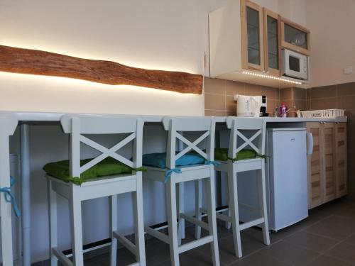 a kitchen with two white stools and a counter at Gyöngyszem Vendégház in Eger