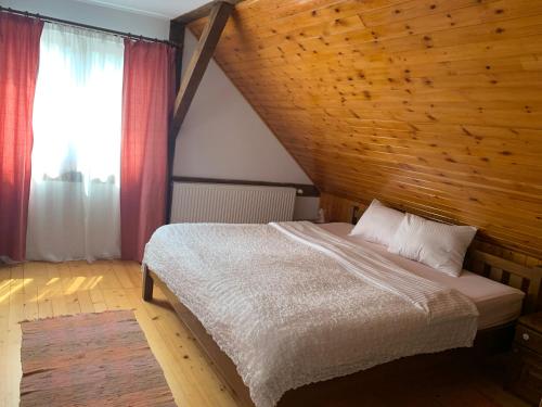 ein Schlafzimmer mit einem Bett mit einer Holzwand in der Unterkunft Casa veche “Old house” in Sibiel