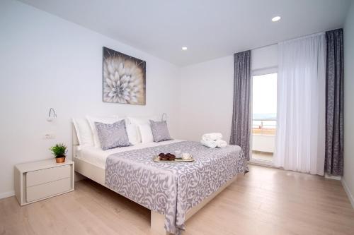 Un dormitorio blanco con una cama y una ventana. en Villa Dasianda - only 90 m from the beach, private 30msq heated pool, en Stanići