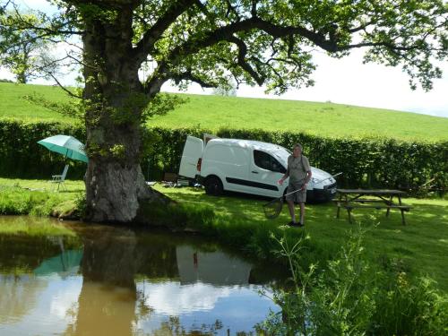 a man standing in front of a van next to a pond at Pound Farm Holidays - Orchard Lodge in Cullompton