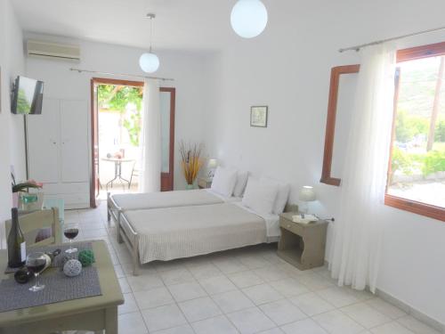 a white bedroom with a bed and a table at Kamakaris Rooms in Adamantas