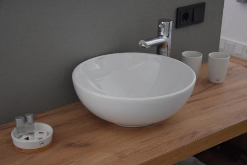 a white bowl sink on a wooden counter with cups at Villa Landlust in Sankt Leonhard
