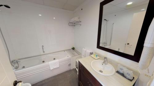 a bathroom with a tub and a sink and a mirror at Hotel Boutique MR Palau Verd - Adults Only in Denia