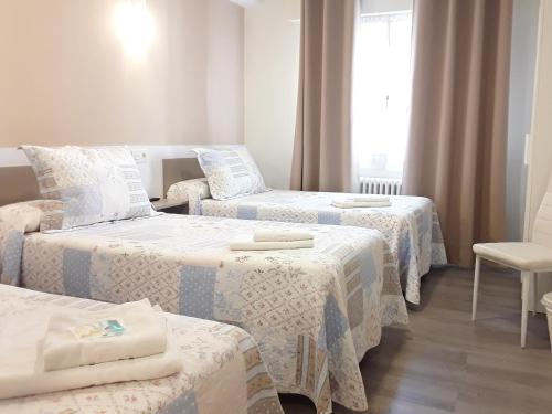 um quarto de hotel com três camas e uma cadeira em Pension Principado em Cangas de Onís