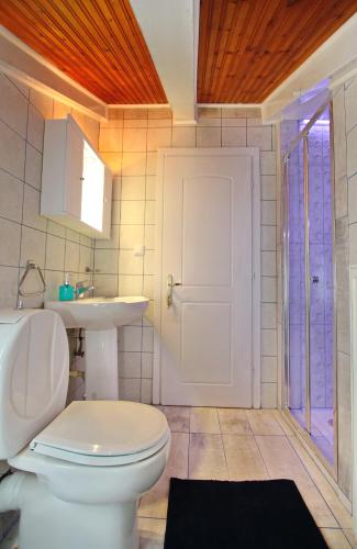 a bathroom with a white toilet and a sink at Coral Suite in Paleo Tsifliki