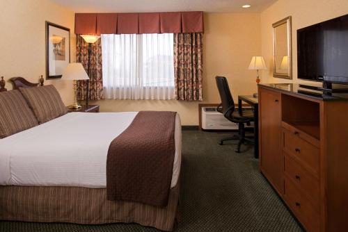 Habitación de hotel con cama, escritorio y TV. en Red Lion Hotel Seattle Airport, en SeaTac