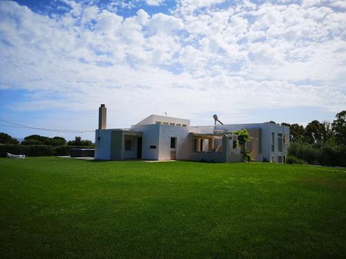 a white house with a green lawn in front of it at Villa Leonidas in Mastichari