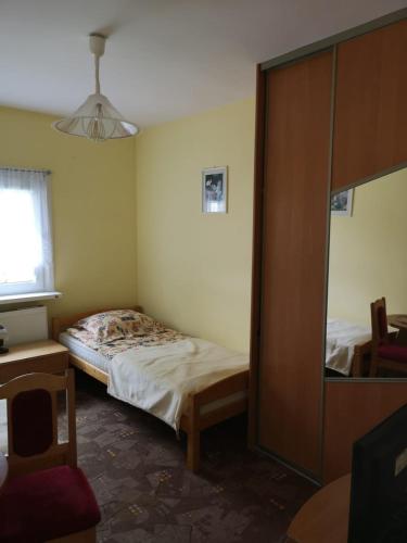 a small bedroom with a bed and a mirror at Mały Biały Domek in Pobierowo