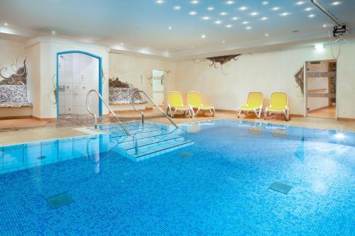 a room with a pool with chairs and a swimming pool at Ferienwohnung Jasmin in Oberstdorf