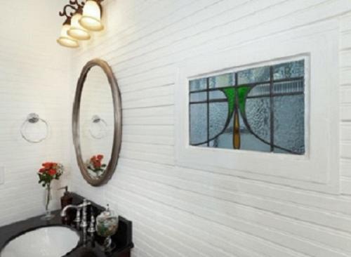 a bathroom with a mirror, a sink, and a painting on the wall at SeaGlass Inn Bed and Breakfast in Melbourne Beach