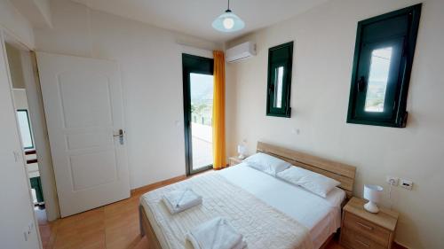 a bedroom with a bed and a large window at Villa Anna in Asprouliánoi
