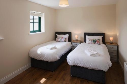 two beds in a small room with two lamps at Oakwell holiday village in Ramelton