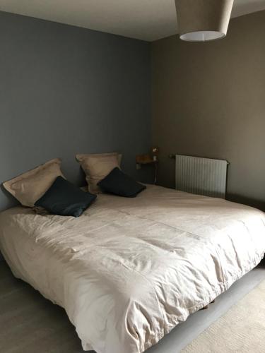 a bedroom with a large white bed with two pillows at Au Rythme des Vagues in Saint-Aubin-sur-Mer