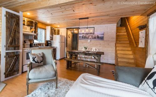 a living room with a couch and a table and a kitchen at Chalet Le Pti Loup - Les Chalets Spa Canada in La Malbaie