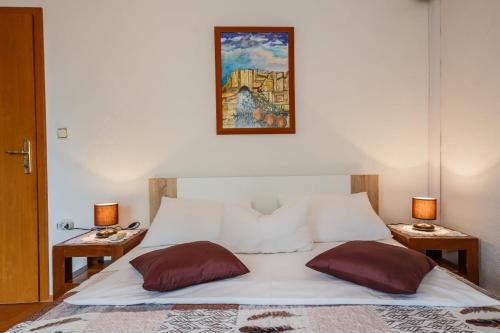 ein Bett mit zwei Kissen und einem Bild an der Wand in der Unterkunft Maria Guest House in Kaštela