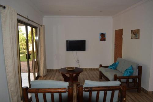 een woonkamer met een tv en een bank en stoelen bij Serviced apartment (3 bedrooms) in Lusaka