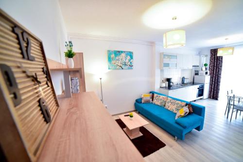 a living room with a blue couch and a kitchen at FLH - Apartament Central Silva in Sibiu