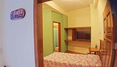 a small bedroom with a bed and a television at Posada Familiar El Dorado in Xilitla