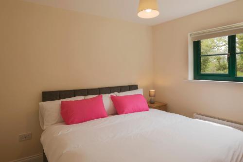 a bedroom with a white bed with pink pillows at Oakwell holiday village in Ramelton