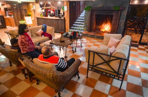 a family sitting in chairs in a living room with a fireplace at Hotel Rancho Constanza & Cabañas de la Montaña in Constanza