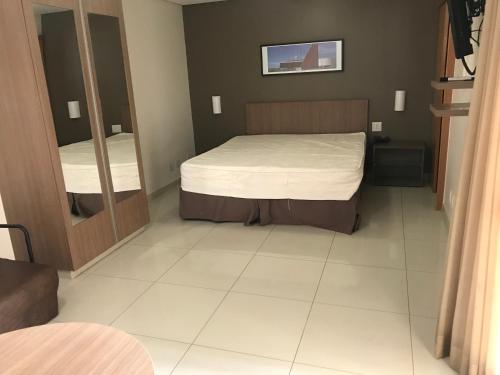 a small bedroom with a bed and a mirror at Crystal Place 2 in Goiânia