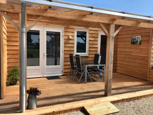 a wooden deck with a table and chairs on it at Camping Lagewald Vakantiehuis in Groesbeek