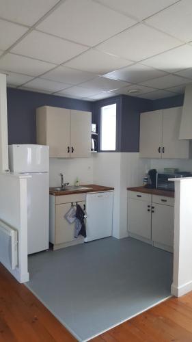 une cuisine avec des armoires blanches et un évier dans l'établissement O'delices du Sancy, à La Bourboule