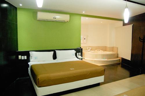 a bedroom with a green wall and a bed and a tub at Hotel Porto Novo in Veracruz