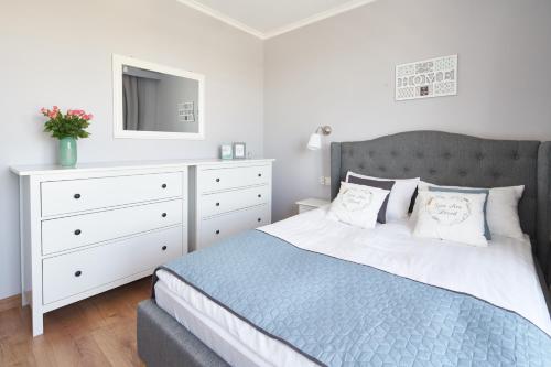 a bedroom with a bed and a dresser with a mirror at Apartament Premium Aquatower Reda in Reda