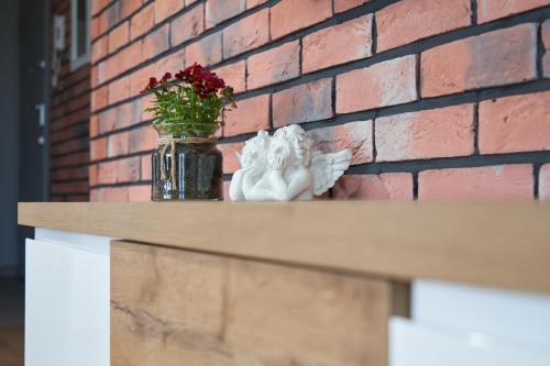 a vase of angels sitting on a table next to a brick wall at Apartament Premium Aquatower Reda in Reda