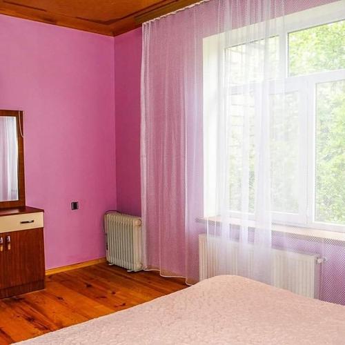 um quarto com paredes cor-de-rosa, uma janela e uma cama em ElVin em Quba