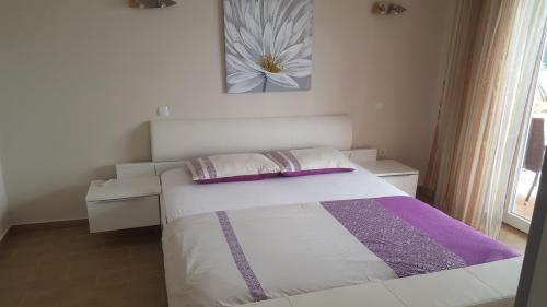a bedroom with a bed and a table and a painting at Banjol 441 Apartman mare in Rab