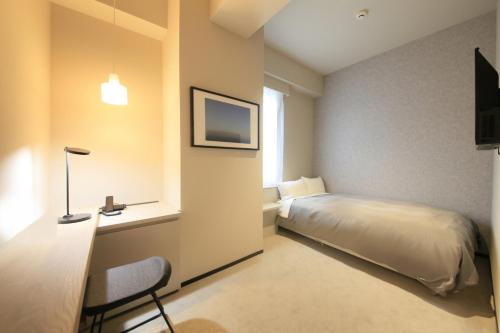 1 dormitorio con 1 cama, escritorio y TV en Center Hotel Tokyo, en Tokio