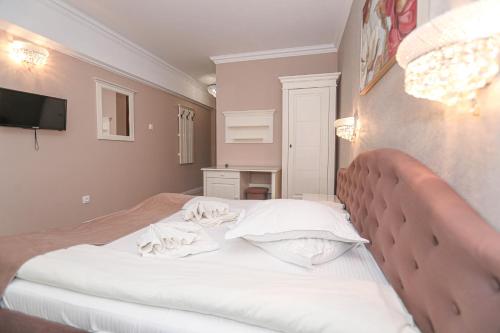a bedroom with a large white bed with a tv on the wall at Pensiune Restaurant Select in Băile Herculane