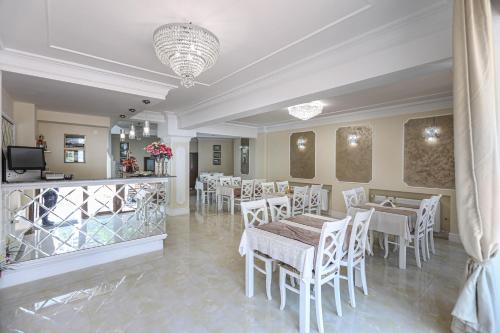 a restaurant with white tables and chairs and a chandelier at Pensiune Restaurant Select in Băile Herculane