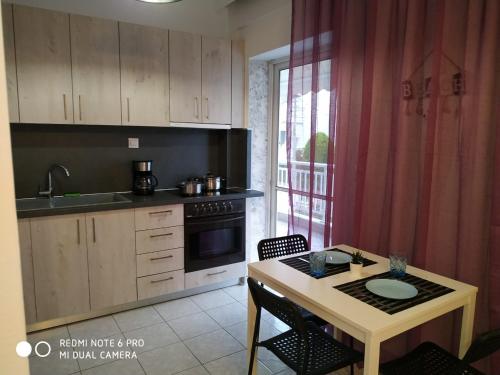 cocina con mesa, fogones, mesa y sillas en Cosi Apartment, en Paralia Dionisiou