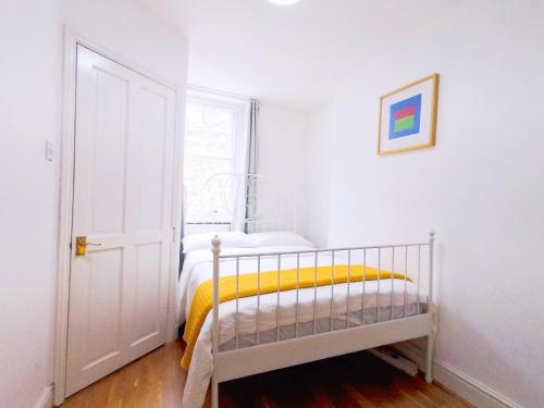 a white bedroom with a bed with a yellow blanket at Orchid 2 At Regent's Park in London