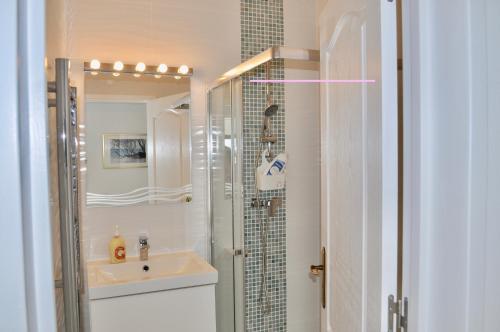 une salle de bain blanche avec lavabo et douche dans l'établissement Apartment Lindamar, à Lagos